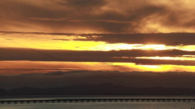 Time-lapse sunset along the straight low section of Astoria Megler bridge Oregon to Washington slow moving clouds through center