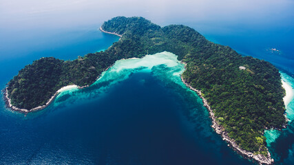 Aerial photo from flying drone of a green island in open sea with calm waves. Amazing nature landscape with Indian Ocean in sunny summer day. Unforgettable vacation in Thailand. Perfect background