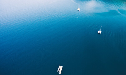 Top view aerial photo from flying drone of a riding catamarans in open sea with calm waves with copy space for your advertising text message or promotional content in summer seasona in Thailand