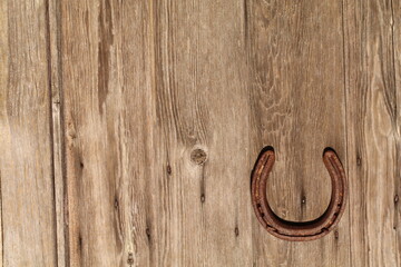 Horseshoe on a wooden surface with wood-grain with knots and cracks