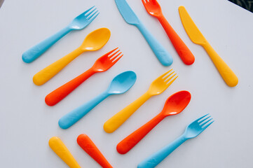 vibrant multicolored forks, kives and spoons (white background)