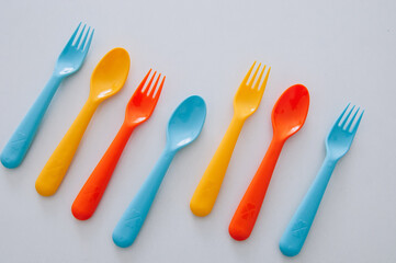 vibrant multicolored forks, kives and spoons (white background)