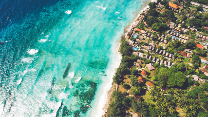 Fototapeta premium Top view aerial drone photo of stunning colored sea beach with crystalline water fringed with swaying tropical palms and leafy trees. Incredibly beautiful blue ocean meet with powder-white seashore