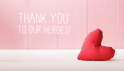Thank You to Our Heroes message with a red heart cushion over a pink wooden wall