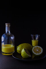 limoncello licor de limón tradicional italiano con botella, copa y mitades de limón fresco