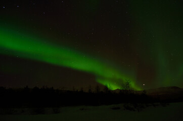 strong aurora borealis, northern light over frozen arctic circle landscape in winter night