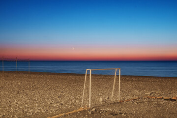 Football goal on the rocky beach with night sky with moon and sea background