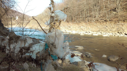 Plastic bags on tree branches near a mountain stream. Pollution of environment. Ecological disaster. 