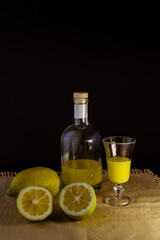 limoncello licor de limón tradicional italiano con botella, copa y mitades de limón fresco