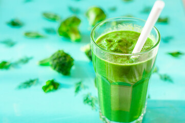 Glass of broccoli juice, on bamboo mat, on green background