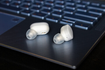 white wireless bluetooth headphones on laptop closeup