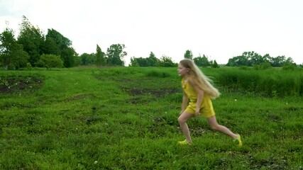 A girl launches into the sky a plane against the background of green grass and blue sky with long blond hair in the village. Summer in nature