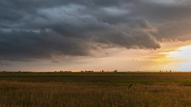Rural landscape and rain clouds moving into the sunset - time lapse.