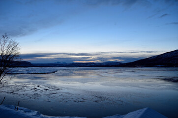 blue frozen fjord and snowy mountain during the blue hour in northern norway