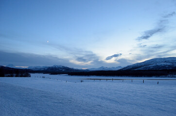 snowy winter pasture with mountain at sunset