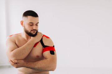 A professional physiotherapist taping stretchy kinesiology tape on patients arm and shoulder. Sport and rehabilitation, kinesio therapy treatment