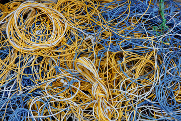 Large pile of white, blue and yellow ropes tied in knots