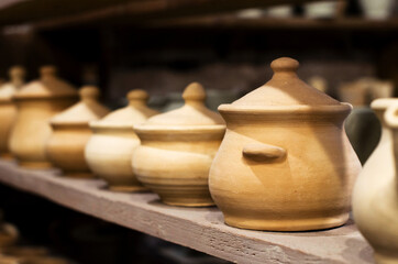 Concept of art therapy. Wooden racks in a pottery workshop in which there are pottery, many different pottery standing on the shelves in a pottery workshop. Master crock. Inside interior. Low light