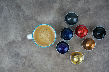 Cup of coffee on a dark background with coffee capsules. Sweet food. Healthy breakfast.
