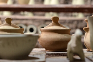 Wooden racks in a pottery workshop in which there are pottery, many different pottery standing on the shelves in a pottery workshop. Master crock. Inside interior. Low light