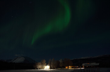 Aurora borealis over homestead in the arctic circle winter night