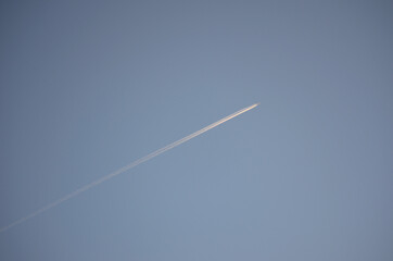Airplane leaves thick condensation stripe on the clear winter sky