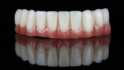 temporary dental prosthesis for the lower jaw, shot on black glass with reflection