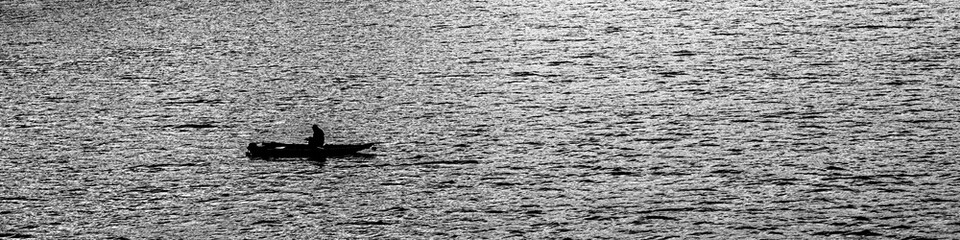 Fisher is sitting in the boat in the river in total silence