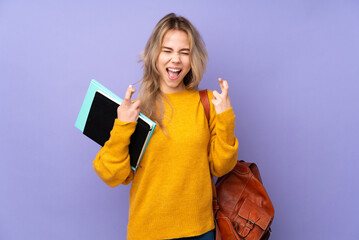 Teenager Russian student girl isolated on purple background with fingers crossing