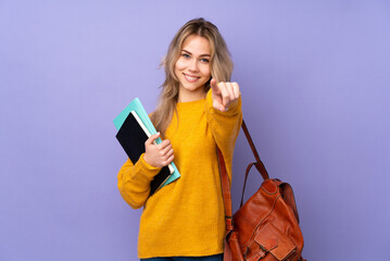 Teenager Russian student girl isolated on purple background points finger at you with a confident...