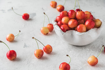 White bowl with ripe orange sweet cherries of sort 'royal anne' on white background