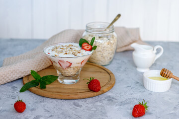 Healthy breakfast of strawberry parfait with fresh fruits, yogurt and granola on a gray table. Oatmeal dessert. Proper, natural nutrition.