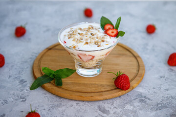 Oatmeal dessert with strawberries. Healthy breakfast of strawberry parfait with fresh fruits, yogurt and granola on a gray table. Proper, natural nutrition. Close-up.