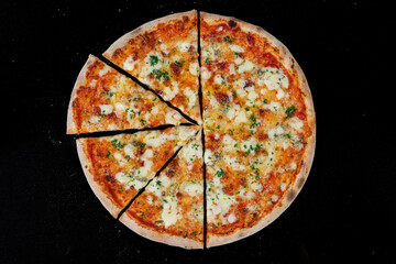 Fresh italian pizza with cheese, ham and tomato  isolated on a black background. View from above.