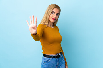 Young Uruguayan blonde woman over isolated blue background happy and counting four with fingers