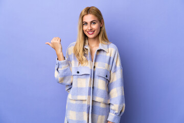 Fototapeta premium Young Uruguayan blonde woman over isolated background pointing to the side to present a product