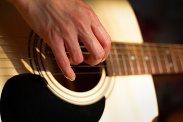 Close up photo of a girl plays the guitar at home. Warm evening sunlight and yellow tones. self-development at home - 359775200