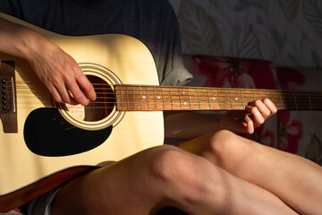 girl plays the guitar at home. Warm evening sunlight and yellow tones. self-development at home - 359775208
