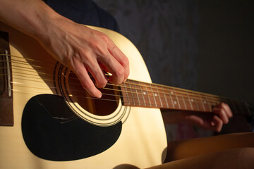 girl plays the guitar at home. Warm evening sunlight and yellow tones. self-development at home