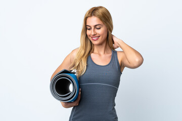 Young sport woman going to yoga classes while holding a mat over isolated white background with...