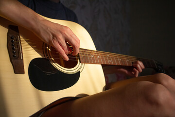 girl plays the guitar at home. Warm evening sunlight and yellow tones. self-development at home - 359775257