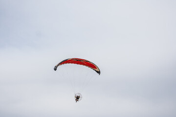 Paramotor vermelho em céu nublado.