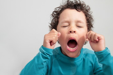 little boy yawning with open mouth on grey background stock photo