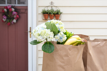 Closeup of paper bags filled with fresh flowers and produce delivered to home doorstep