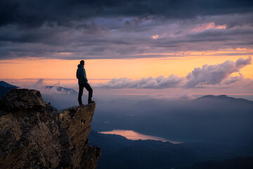 Fantasy Adventure Composite with a Man on top of a Mountain Cliff with Dramatic Landscape in...