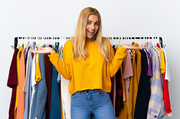 Young Uruguayan blonde woman in a clothing store with shocked facial expression