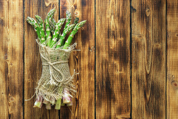Asparagus seedlings tied with a jute cloth on a wooden table.