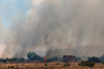 Fototapeta na wymiar Raging Arizona arson wildfire in rural area with firefighters battling pillars of smoke and flame
