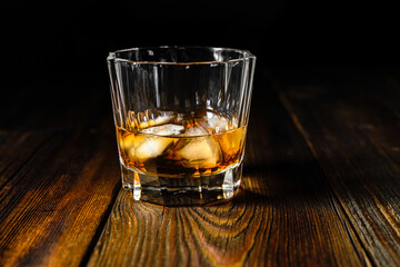 whiskey and ice on a wooden table dark background
