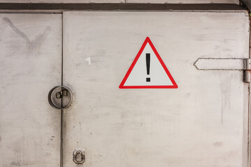 Exclamation mark sign in triangle, danger on gray iron doors